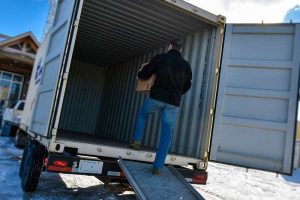 man loading mobile container on truck
