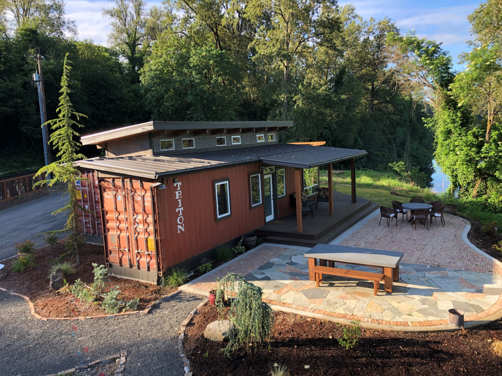 shipping container customized into hom with windows, doors, covered porch to stamped concrete patio and raised ceiling.