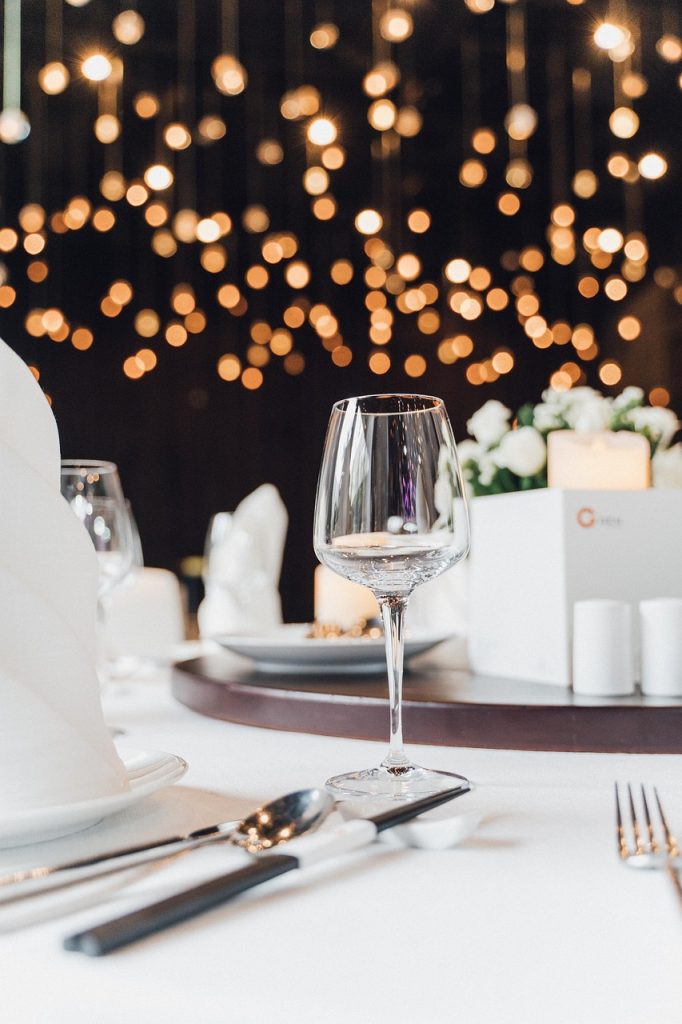 A place setting at a wedding. It has strings of white lights behind it.